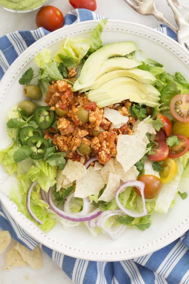 White bowl with tossed salad topped with Cuban picadillo recipe.