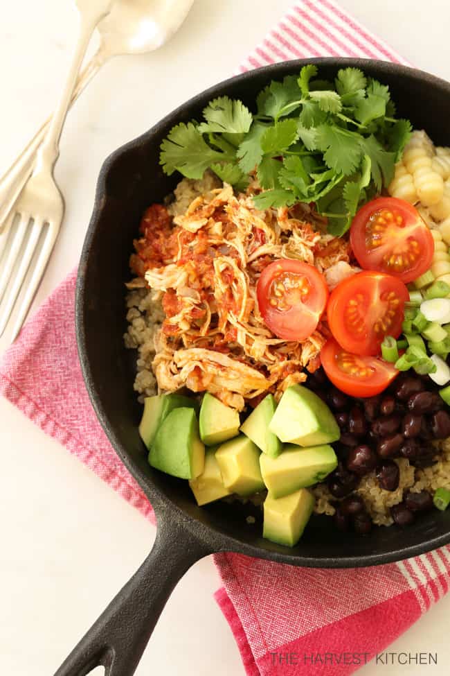 Cast iron pan filled with Mexican Style Shredded Chicken , quinoa, black beans, avocado and sliced cherry tomatoes.