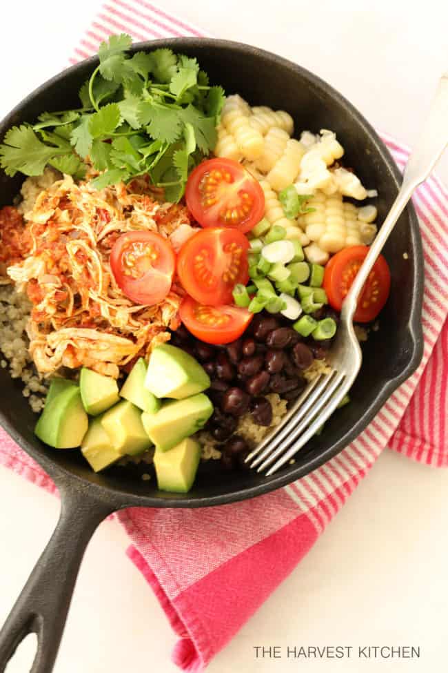 Cast iron pan filled with Mexican Style Shredded Chicken , quinoa, black beans, avocado and sliced cherry tomatoes.