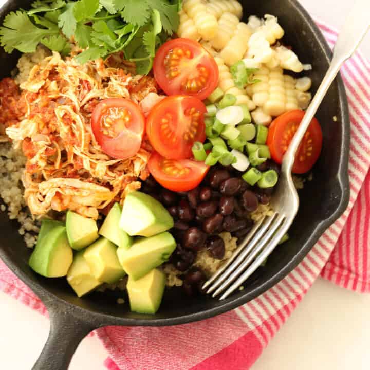 Cast iron pan filled with Mexican Style Shredded Chicken , quinoa, black beans, avocado and sliced cherry tomatoes.