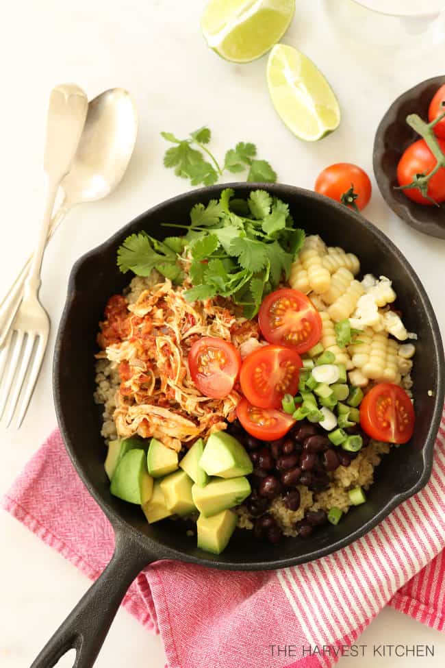 Cast iron pan filled with Mexican Style Shredded Chicken , quinoa, black beans, avocado and sliced cherry tomatoes.