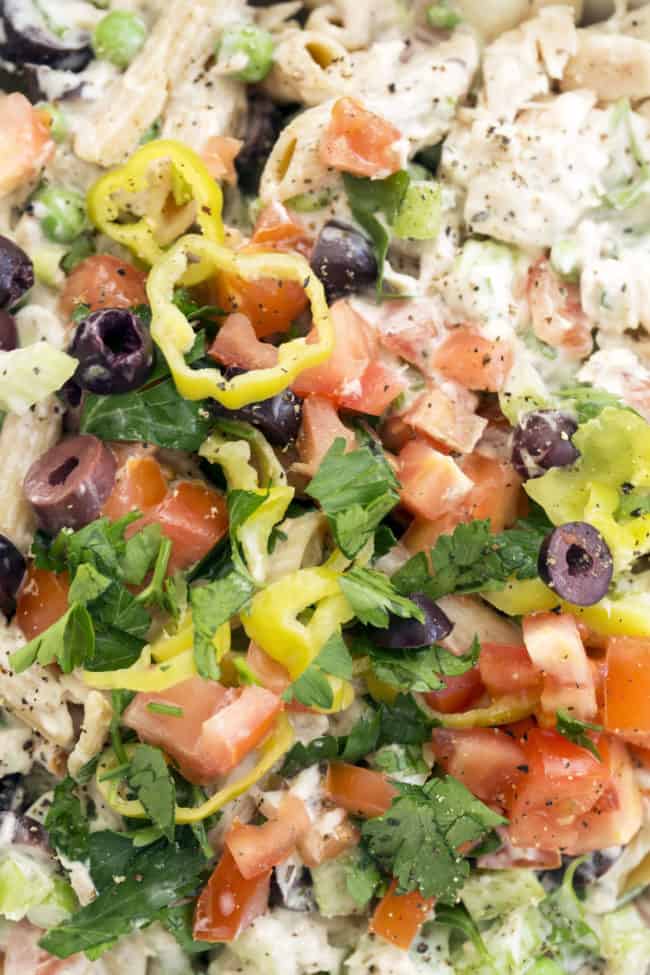 White bowl filled with penned noodles, canned tuna and vegetables tossed in a dressing.