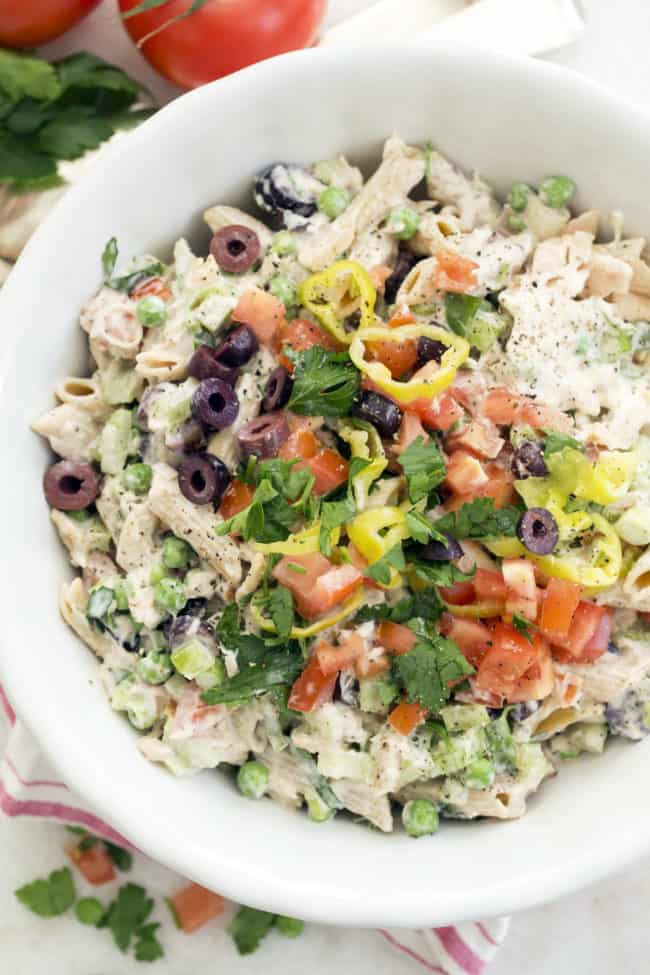 White bowl filled with penned noodles, canned tuna and vegetables tossed in a dressing.