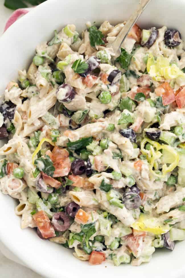 A white bowl filled with cold tuna pasta salad (penne noodles, canned tuna, and vegetables tossed in a dressing).