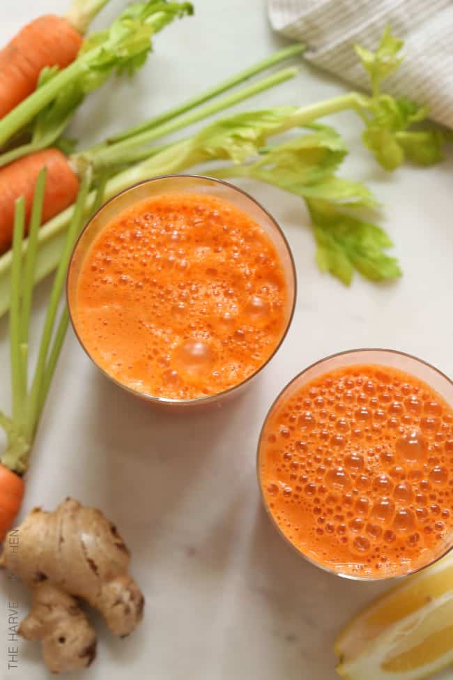 glasses of carrot juice (healthy juice recipes) with carrots, celery and ginger root next to them