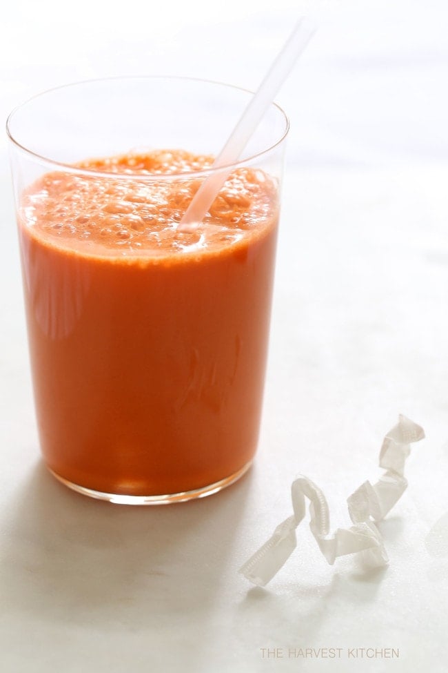 glass of carrot juice with a straw in it