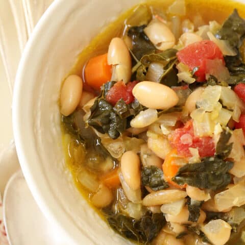 A white bowl filled with white bean kale soup.