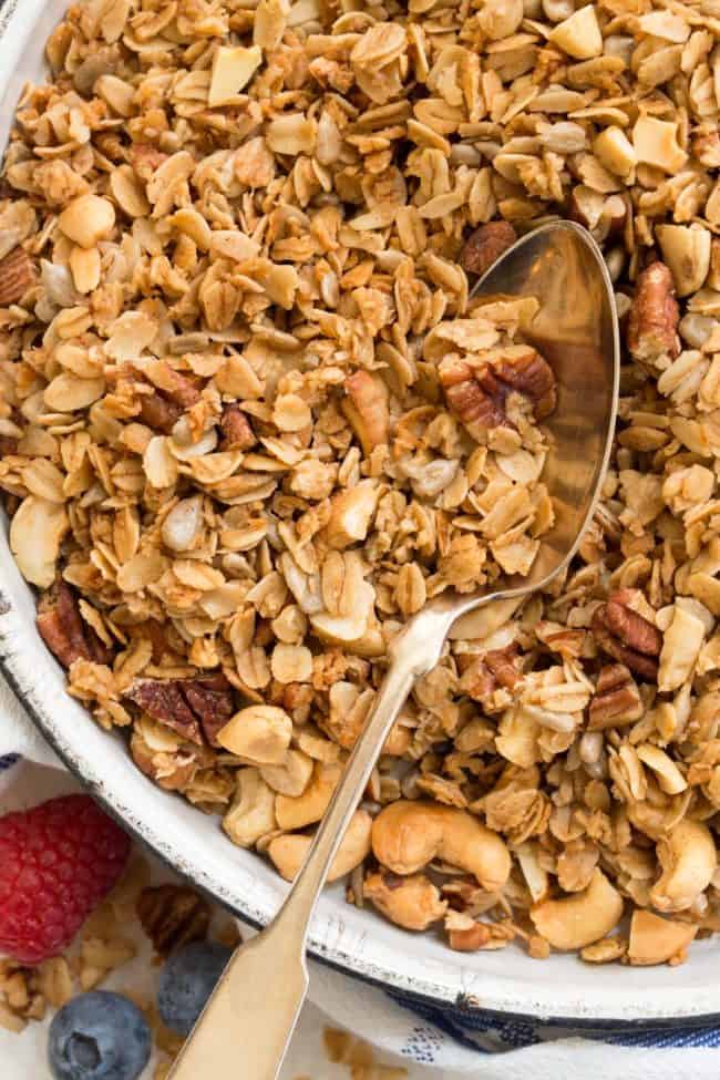 A white plate filled with homemade healthy granola. A spoon rests on the plate.