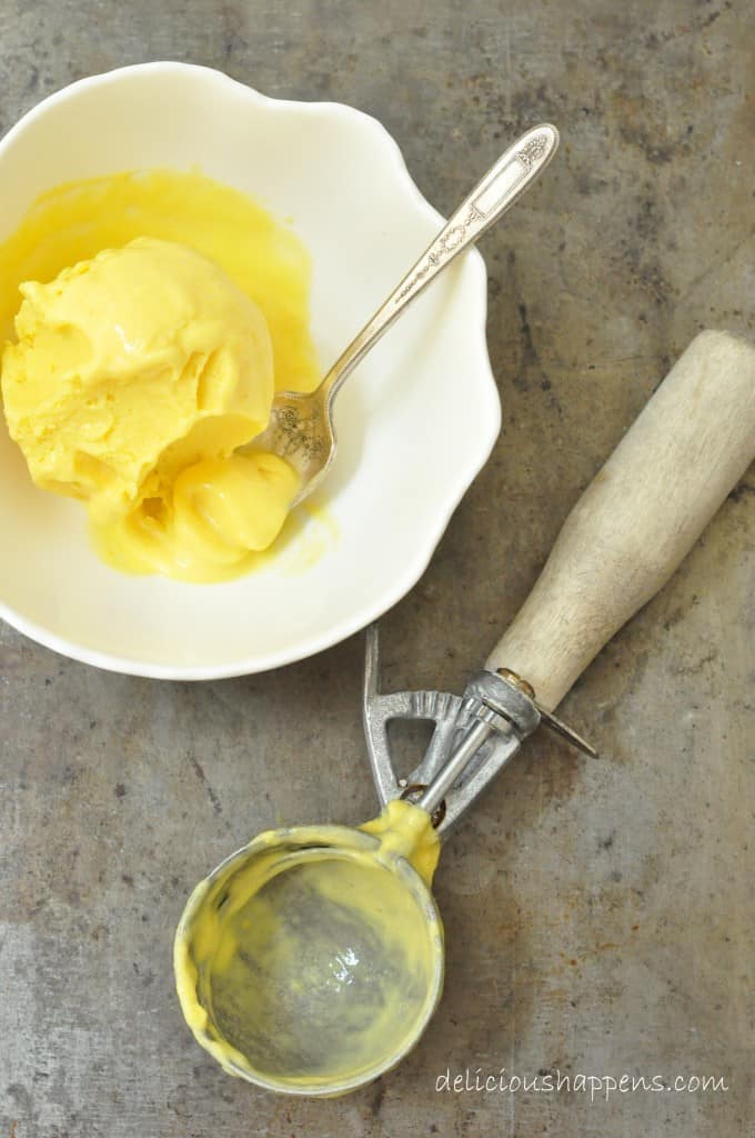 A white bowl filled with orange colored frozen dessert. 