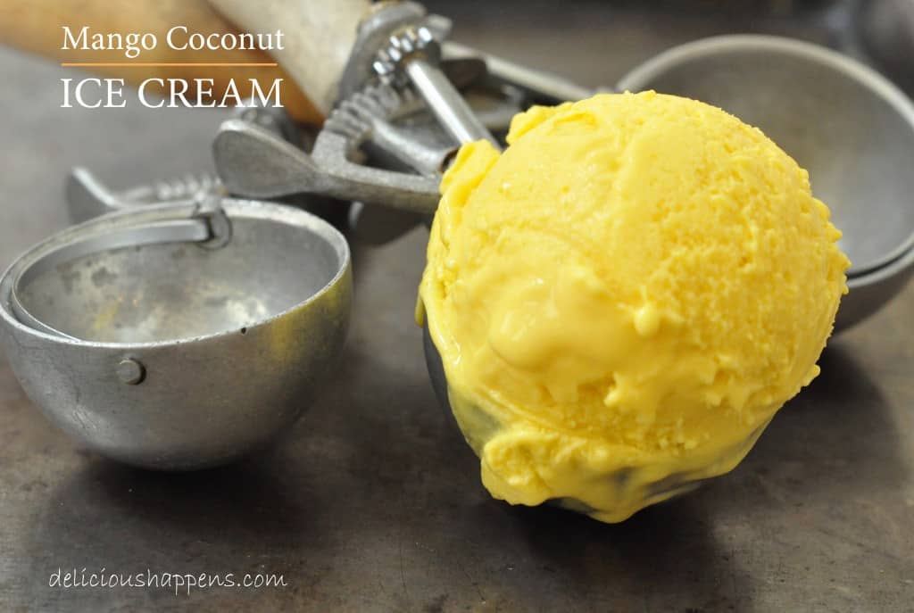 Three ice cream scoops with wooden handles. One of the scoops is filled with orange colored ice cream.