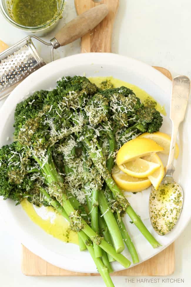 A white plate filled with steamed basil pesto broccoli. 