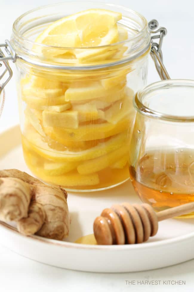 A clear glass mason jar filled with lemon honey and ginger slices.