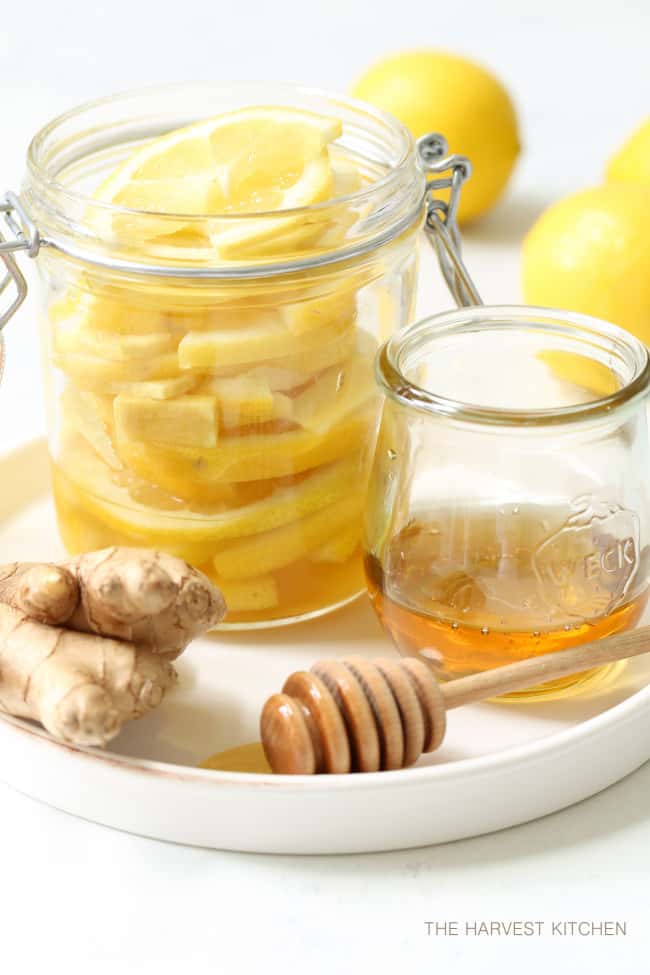 A clear mason jar filled with lemon honey and ginger slices.