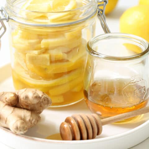 A clear glass mason jar filled with honey lemon and ginger slices.