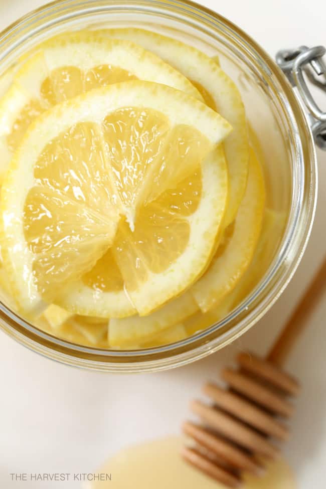 A clear glass mason jar filled with honey lemon ginger slices.