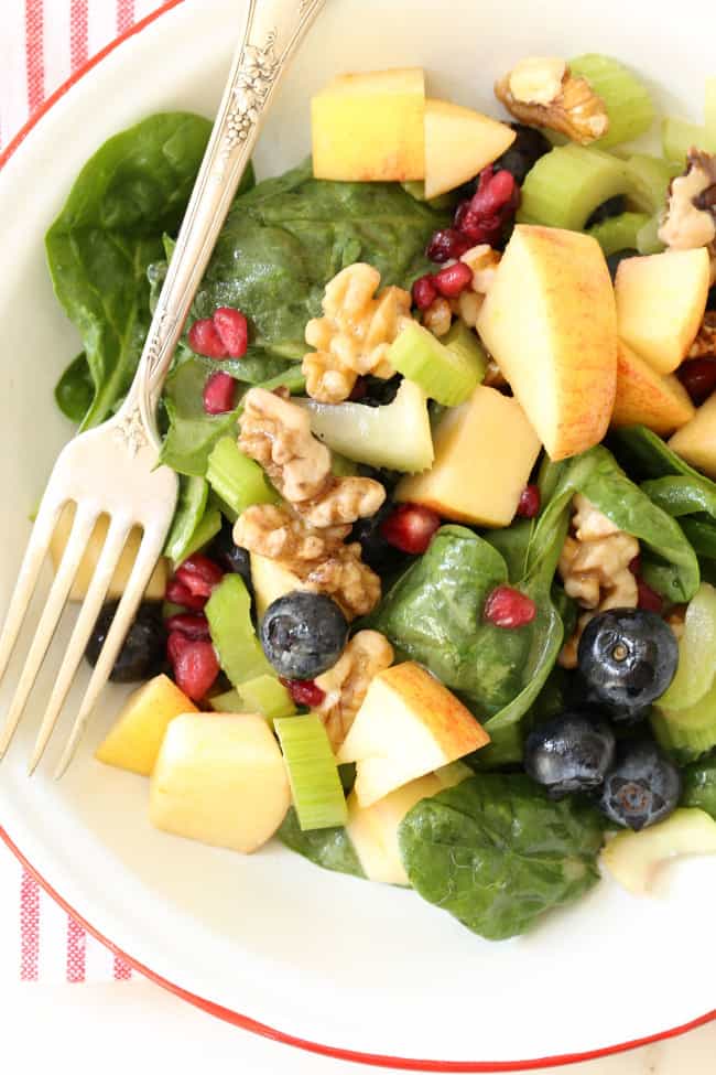A white bowl of spinach blueberry salad.
