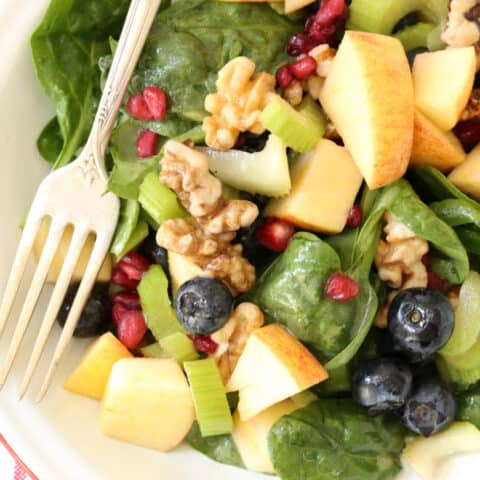 A white bowl filled with Spinach Blueberry Salad.