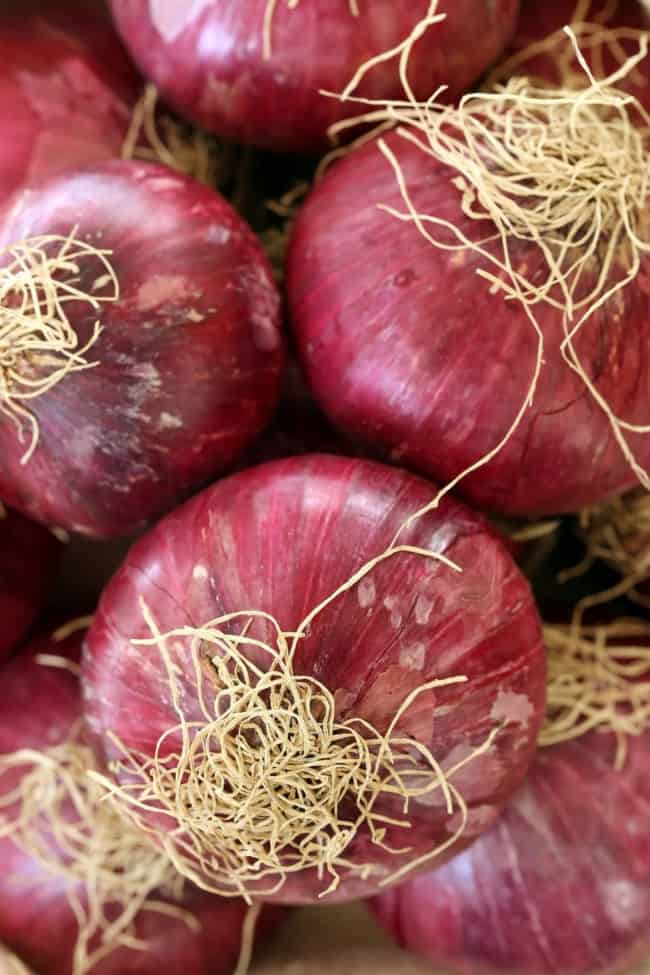 Several red onions scattered on a counter top.