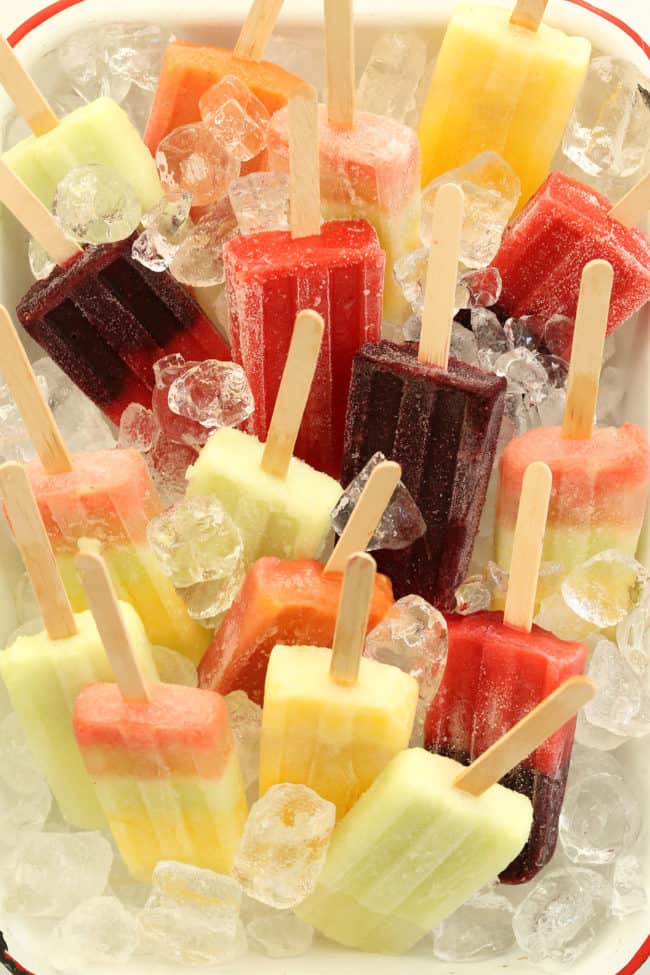 A white tray filled with a variety of coconut water fruit popsicles.