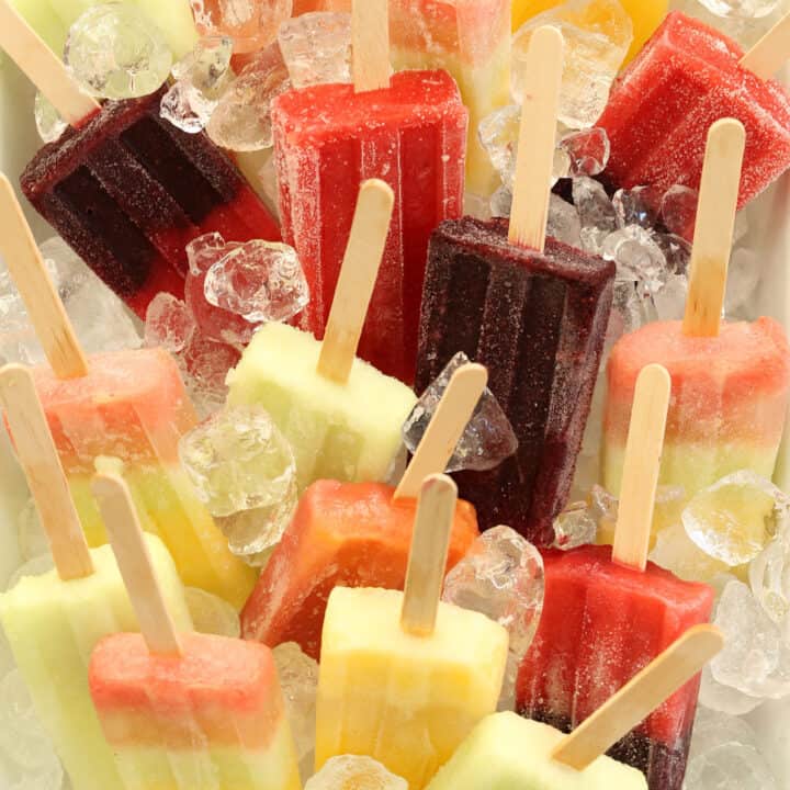 A white bowl filled with ice and Coconut Water Fruit Popsicles.