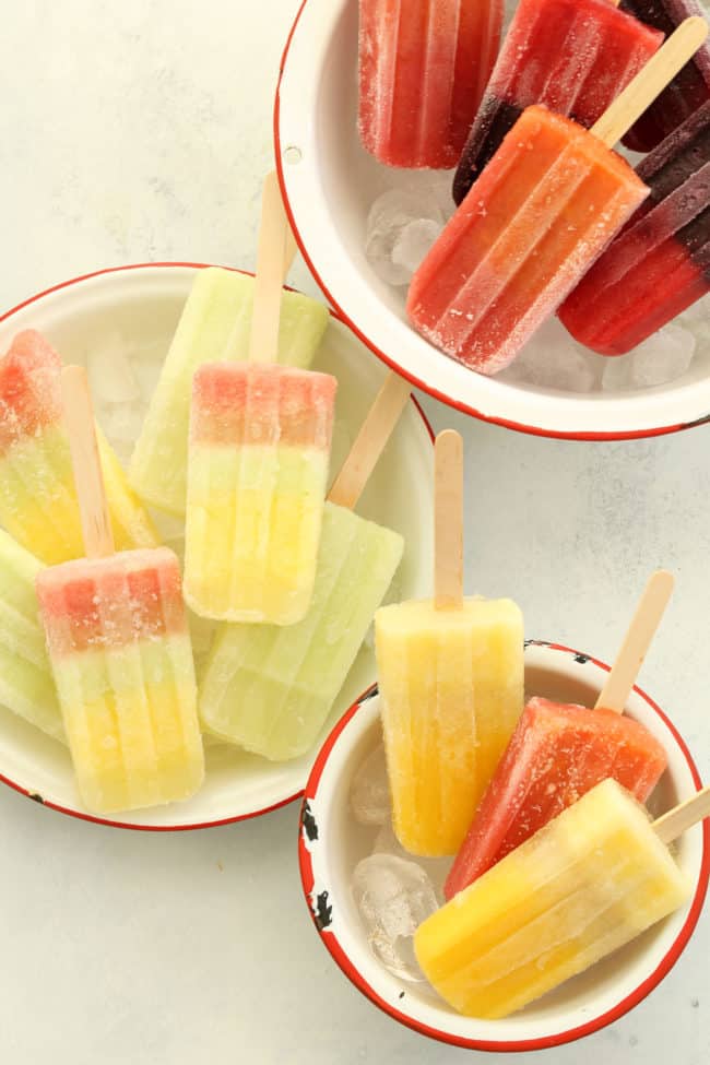 Three white bowls filled with ice and frozen fruit pops.