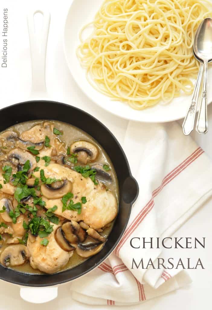 A black cast iron skillet filled with chicken marsala with mushrooms. A bowl of pasta sits next to the skillet