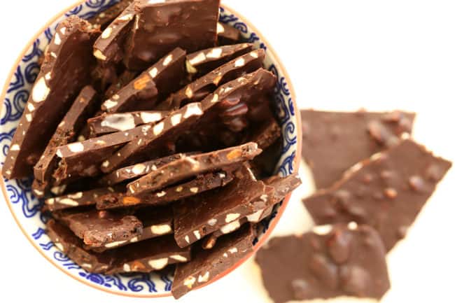 A blue and white bowl filled with candy coated nuts.