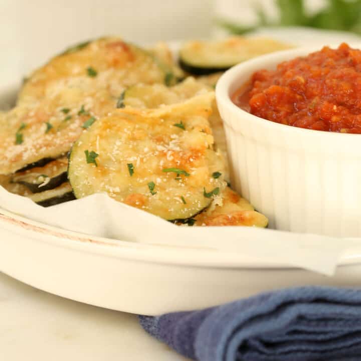 A white serving dish filled with Baked Zucchini Chips.