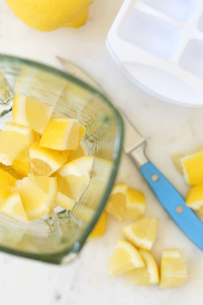 A glass blender filled with chopped citrus.