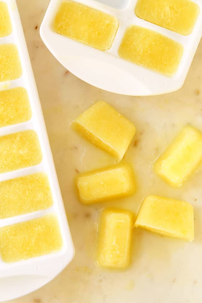 White ice cube trays filled with whole lemon ice cubes.