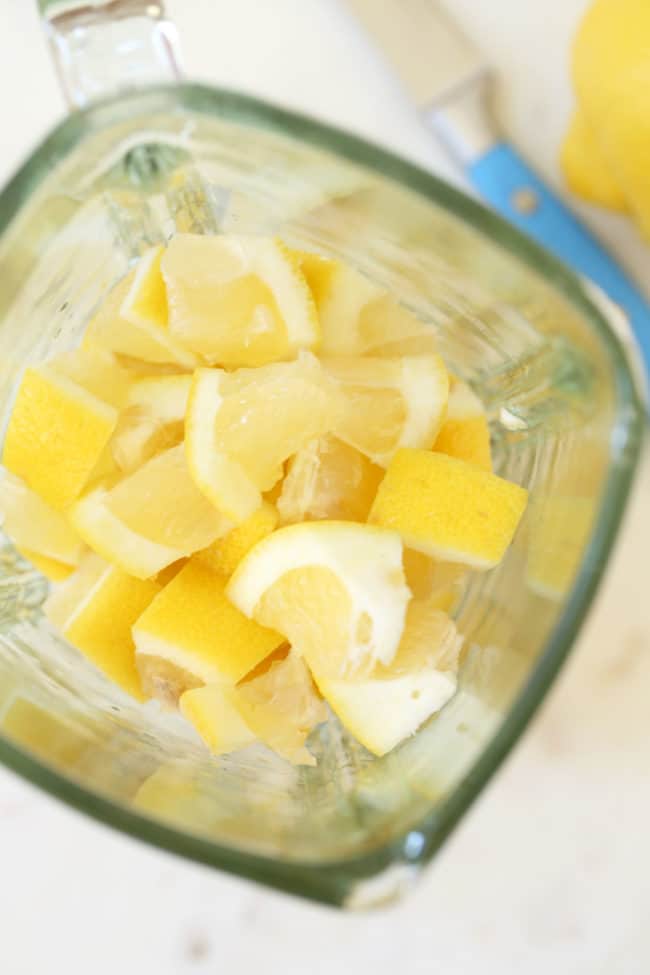 A glass blender filled with chopped lemons to make whole lemon ice cubes.