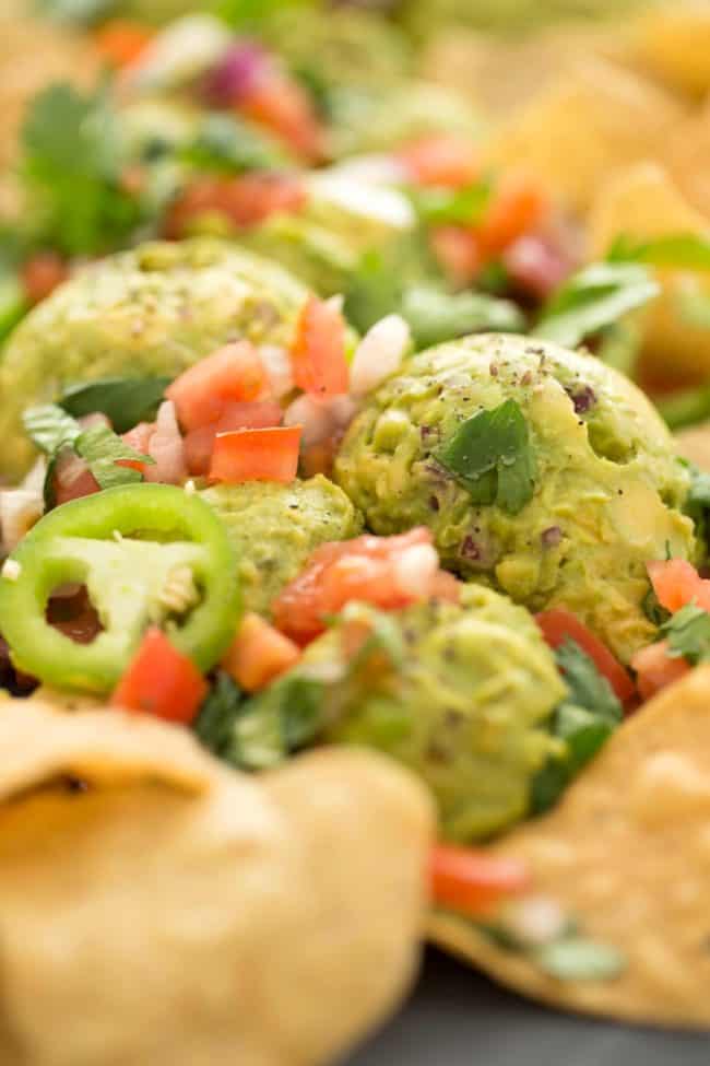 Scoops of chunky 4 ingredient guacamole on a platter with pico de gallo and tortilla chips