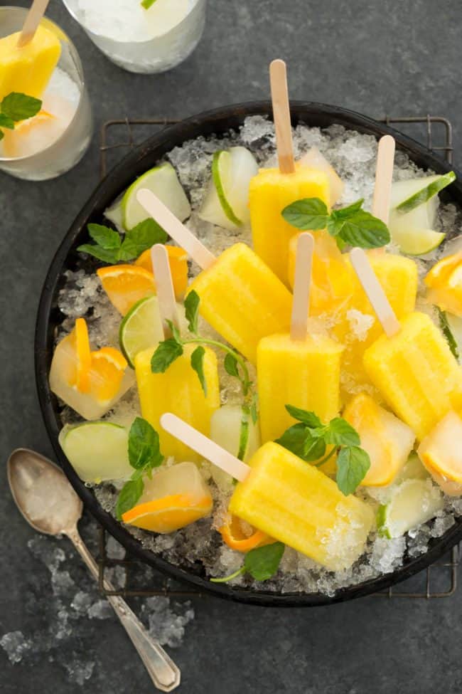 A round black tray filled with crushed ice and Mexican popsicles.