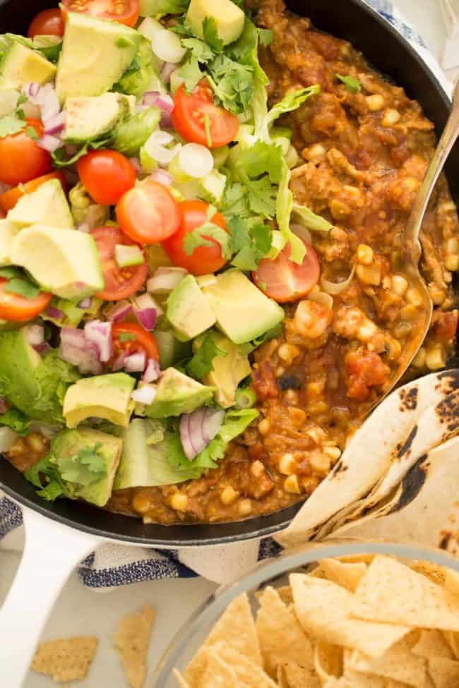A white pan filled with ground turkey and refried beans for taco skillet.