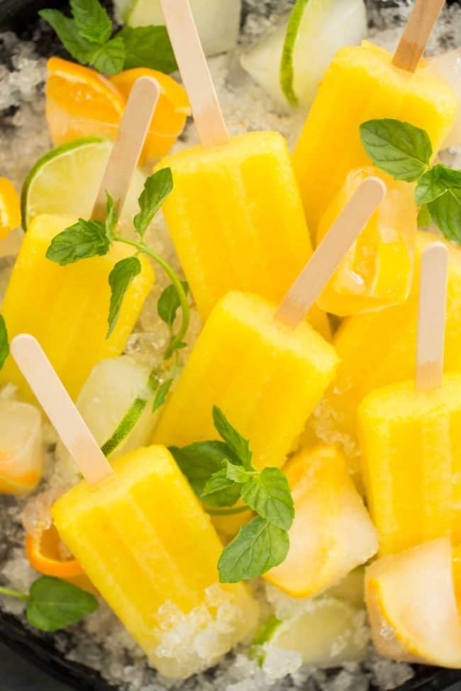 A round black tray filled with crushed ice and popsicles.