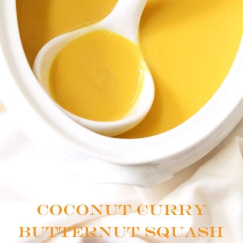A white soup tureen filled with coconut curry butternut squash soup. A white ladle rests in the tureen.