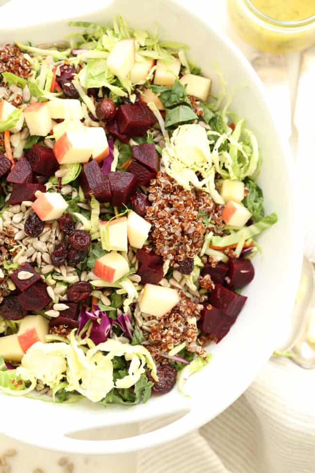 A white bowl of tossed greens and chopped beets.