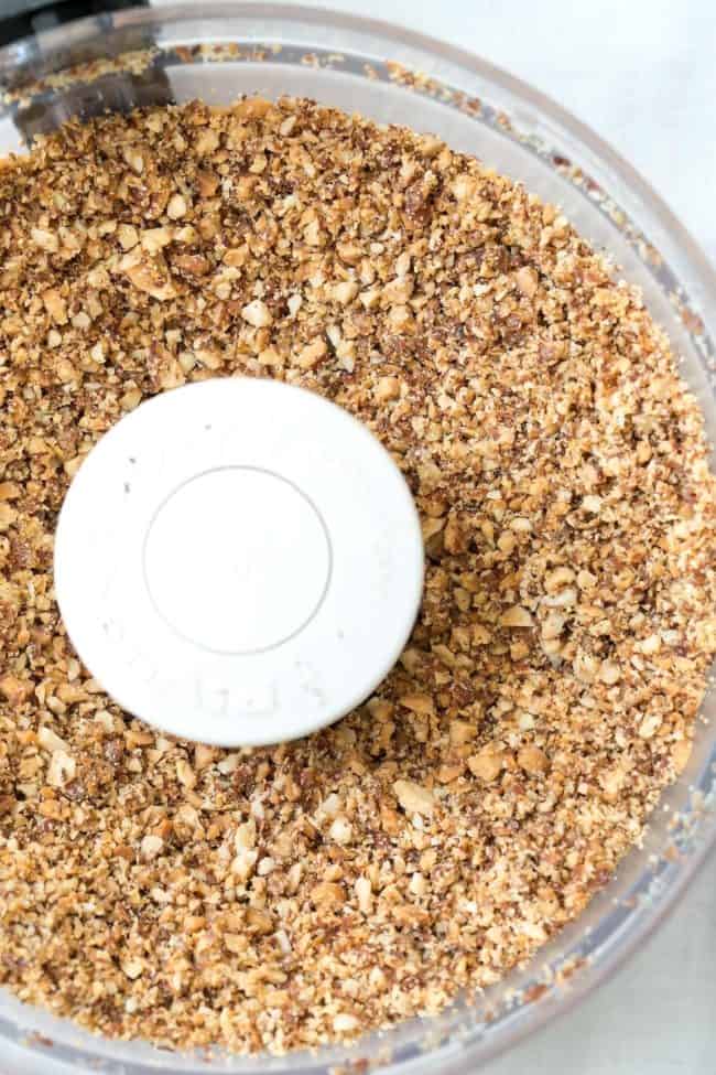 A food processor bowl filled with ground nuts