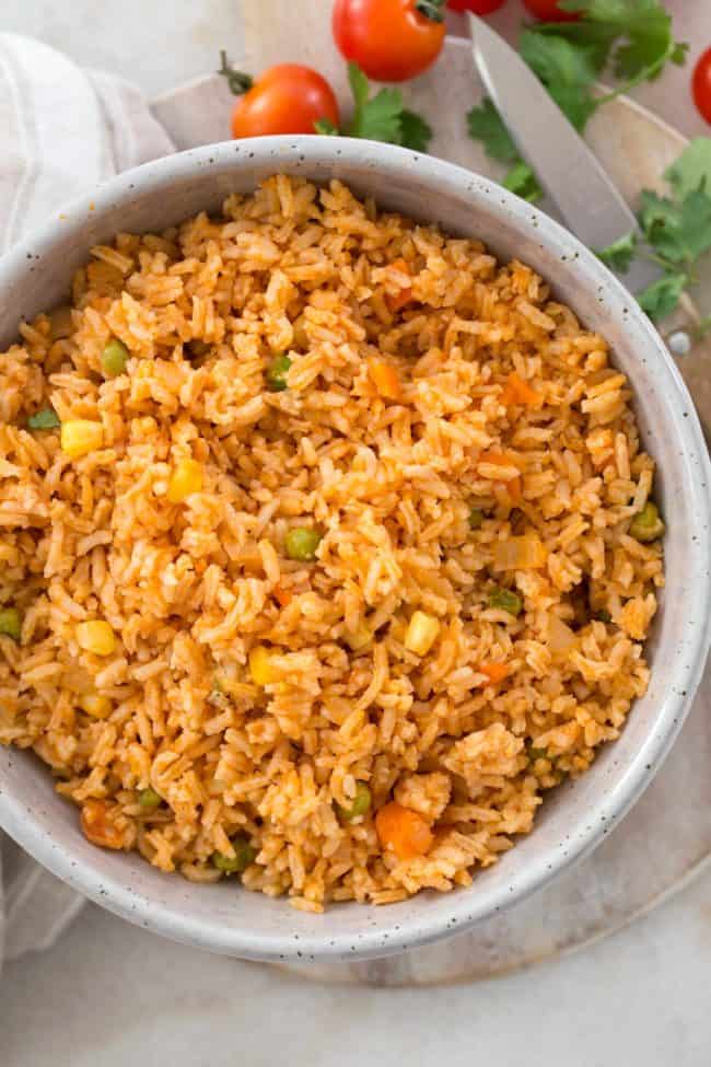 Bowl of grains cooked with peas, carrots and corn.