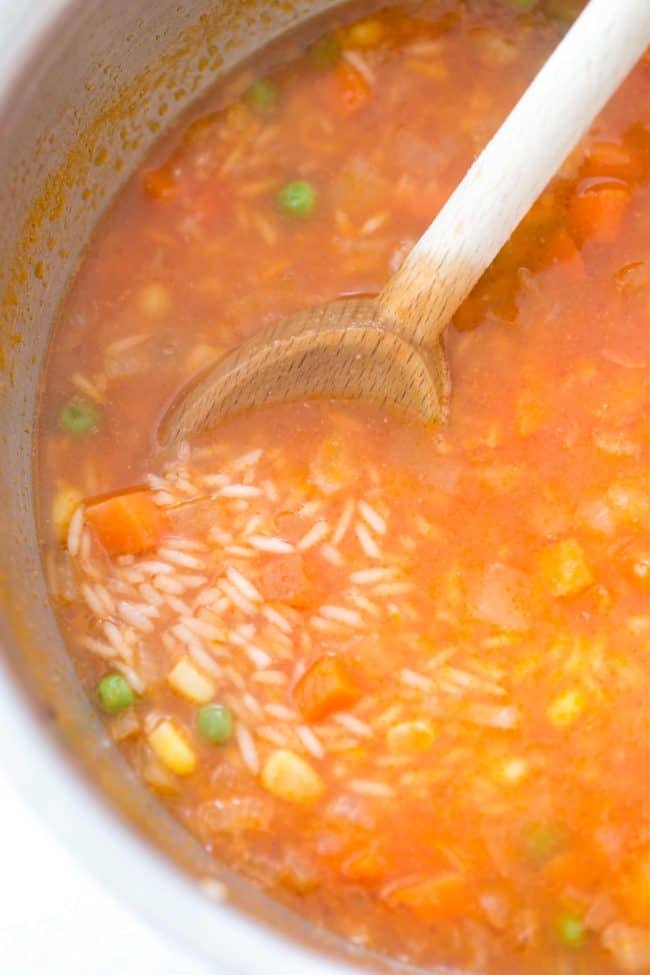 A pot of grains cooking in a broth with vegetables.