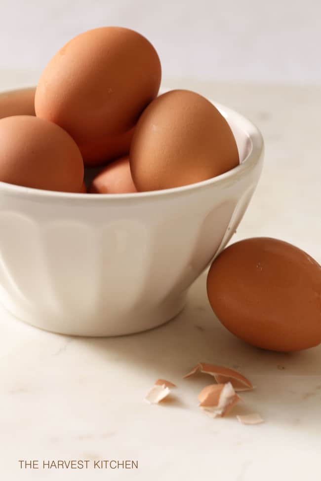 A white bowl filled with brown hen eggs.