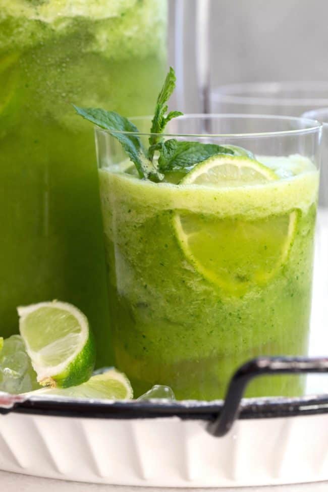 A clear glass filled with green juice.