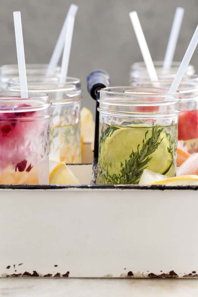 Several glasses filled with clear liquid and straws.