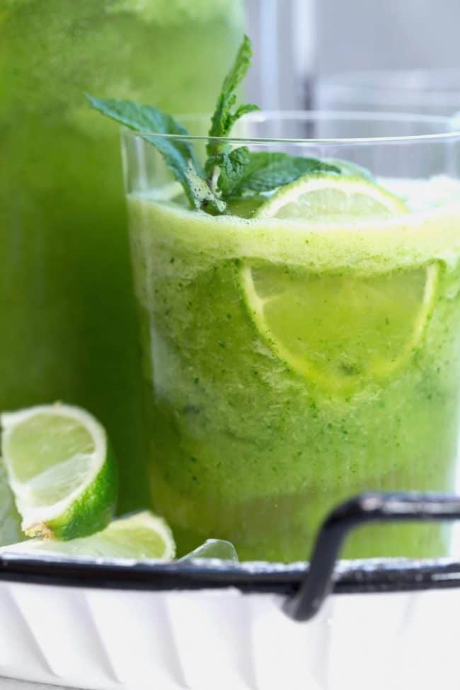 A clear glass filled with green juice.