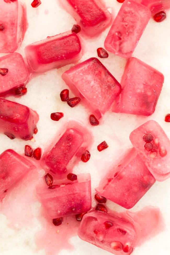 Fruit ice cubes melting on a white marble counter.