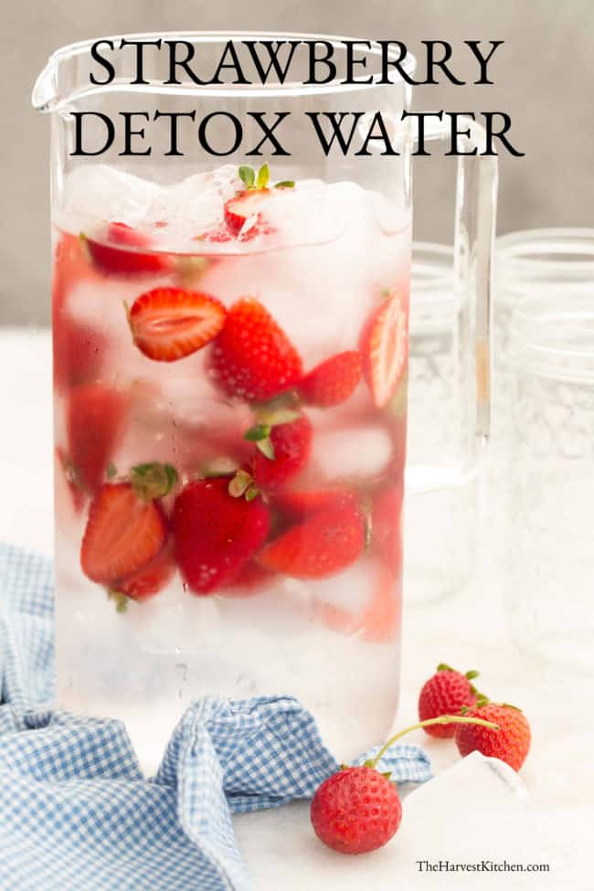 A clear pitcher of water with strawberries.