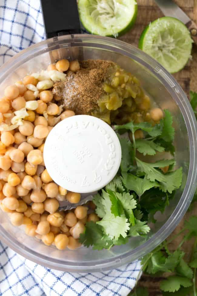 A food processor filled with chickpeas and fresh cilantro.