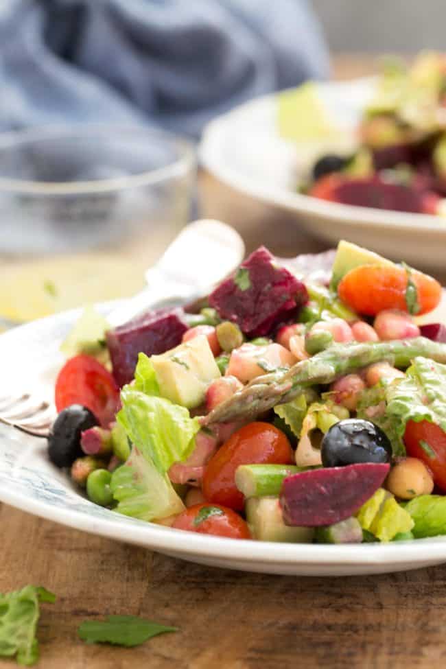 White plates with lettuce, chopped beets, asparagus, blueberries and cherry tomatoes. 