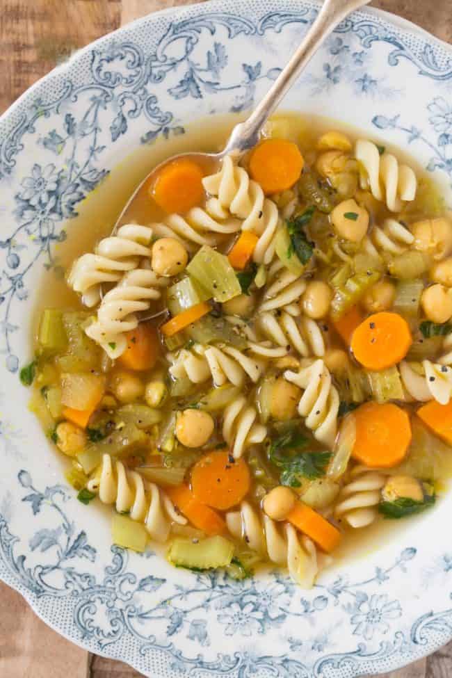 A blue and white bowl filled with chickpea noodle soup.