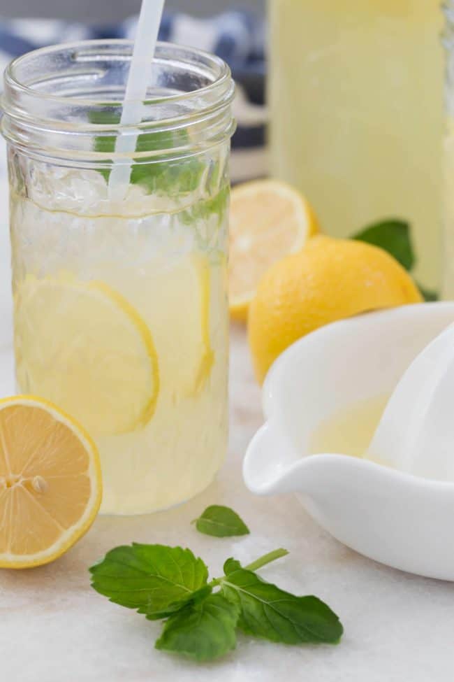 A glass filled with citrus juice sits next to a white juicer 